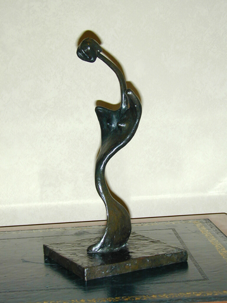 Emily - a semi-abstract standing sculpture figure in bronze. Viewed from the left, her body forms an S shape. She has a very long neck and a head reminiscent of Stephen Spielberg's ET.