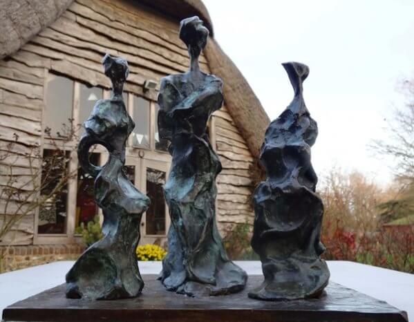 Three Sisters in front of Barn - semi-abstract bronze sculpture of three standing figures