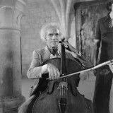 Paul Tortelier - cellist playing for a recording in a stone, gothic building. The C-string is vibrating in the photo.