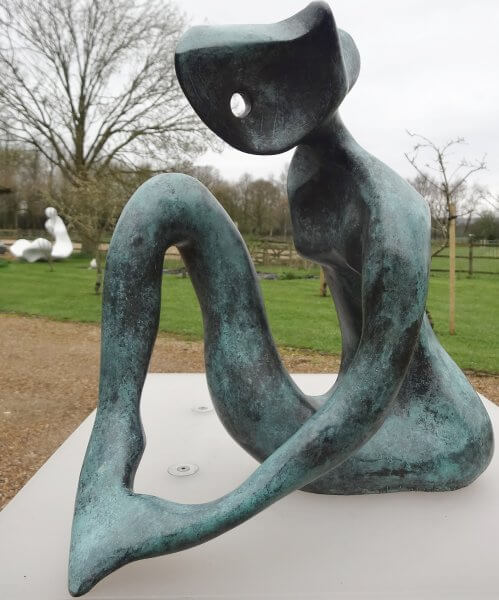 Contemplation - an abstract sculpture of a figure in bronze. The figure's left arm appears to be holding its left foot. The finish is a mottled verdigris colour.