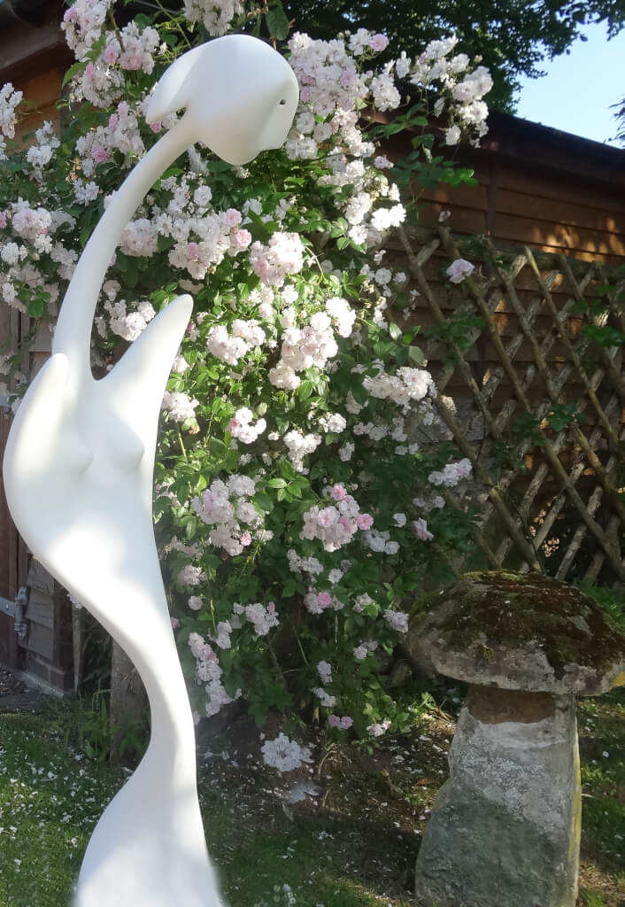 Florence - asbtract sculpture in white resin in front of a bush of red roses