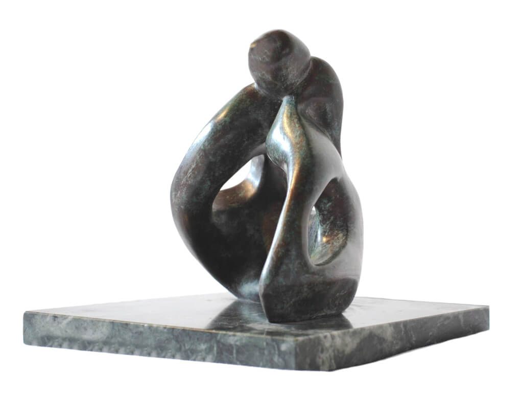 Low view of abstract bronze sculpture of couple sitting on the ground kissing from the Gibran Sculpture Series. Marble plinth.