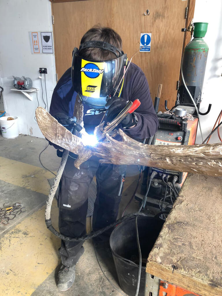 Argon welding the dove to the top of the Speak to us of Freedom bronze sculpture in the foundry.